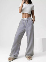 Person wearing a white crop top and black and white striped pants on a white background