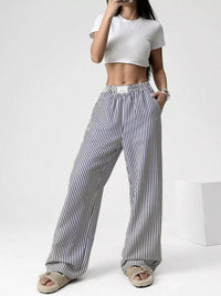 Person wearing a white crop top and black and white striped pants on a white background