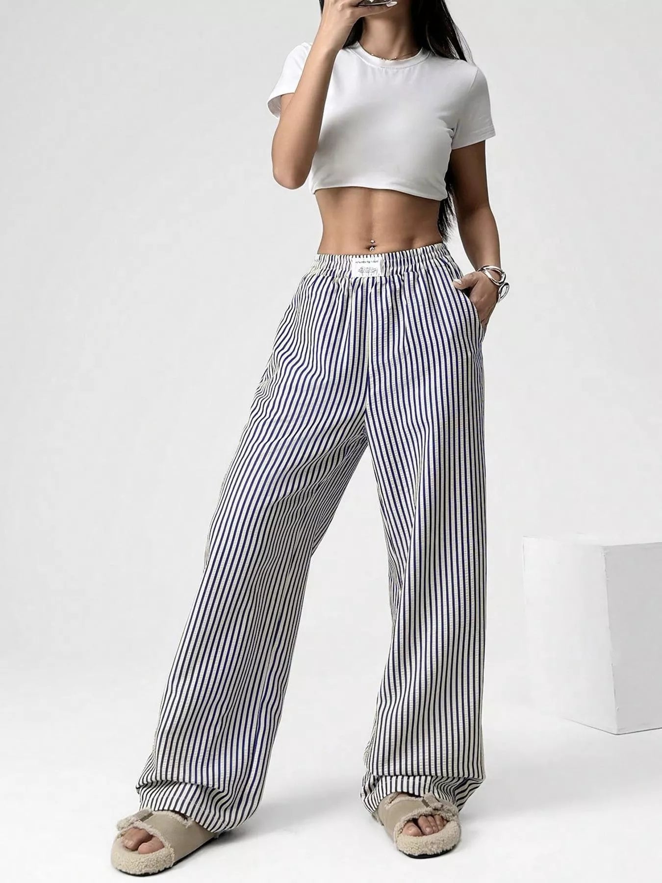 Person wearing a white crop top and black and white striped pants on a white background