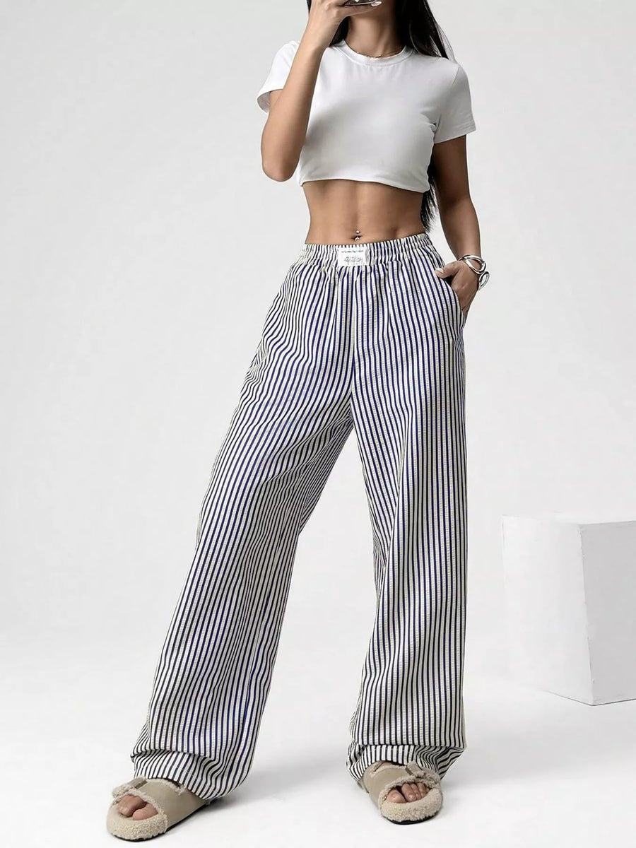 Person wearing a white crop top and black and white striped pants on a white background