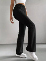 Person wearing black ribbed pants and white sneakers on a gray background