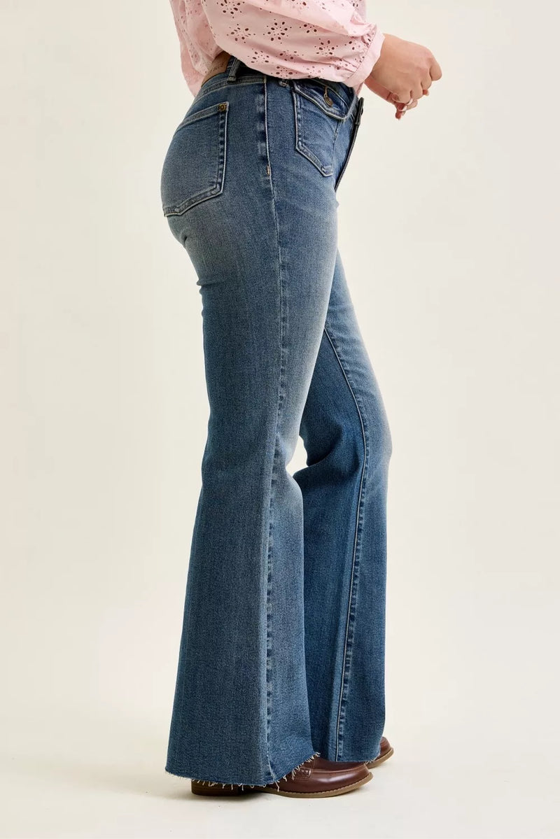 Person wearing blue flared jeans on a beige background