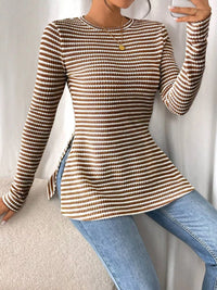 Person wearing a brown and beige striped sweater with blue jeans on a neutral background