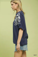 Woman wearing a navy blue top with white floral patterns on a light green background