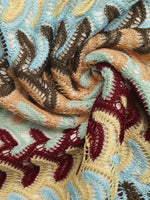 Close-up of textured fabric with intricate patterns in brown, blue, and red.