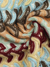 Close-up of textured fabric with intricate patterns in brown, blue, and red.