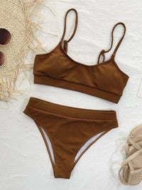Brown bikini set on a light background with a straw hat and sandals.