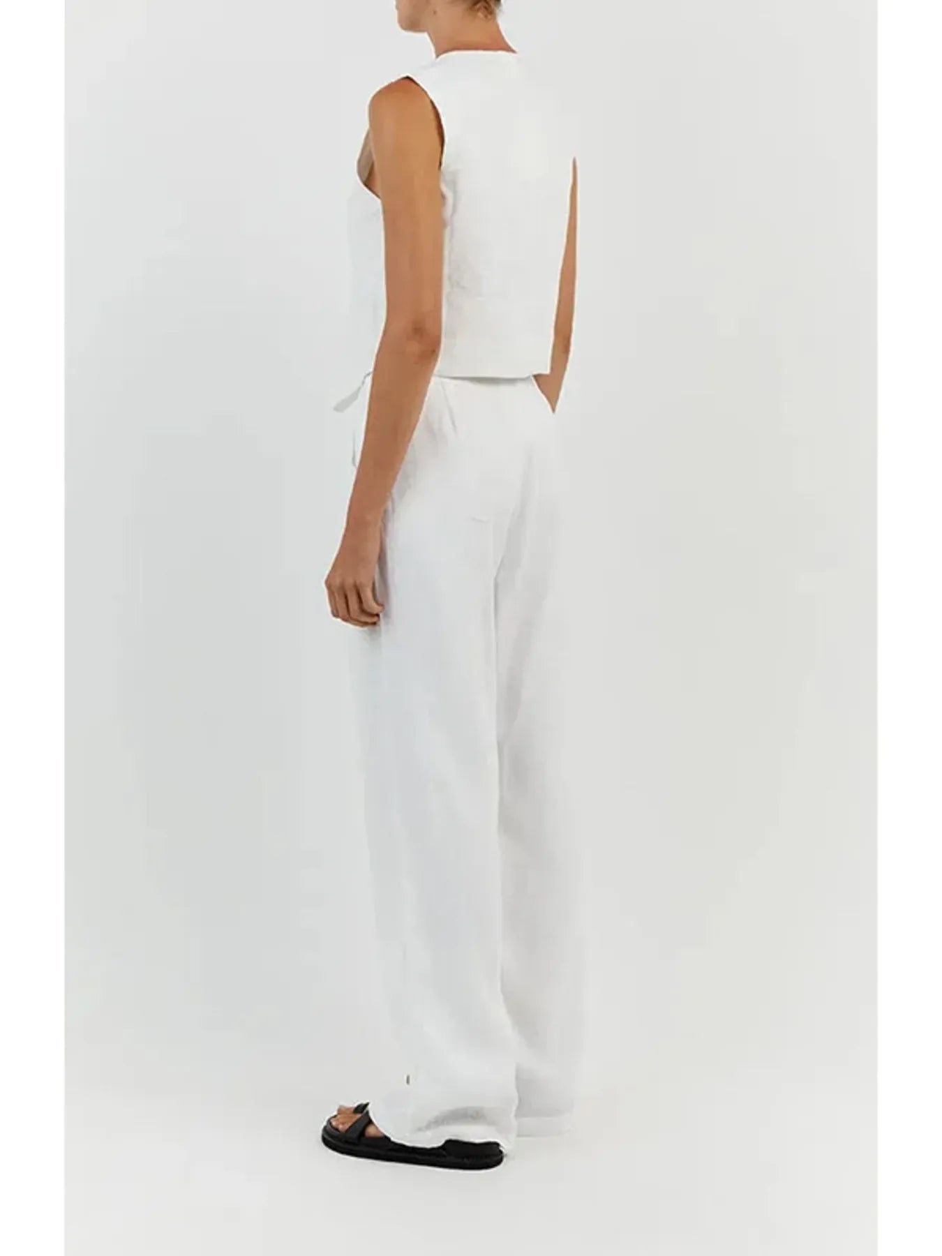 Person wearing a white sleeveless top and pants on a plain background