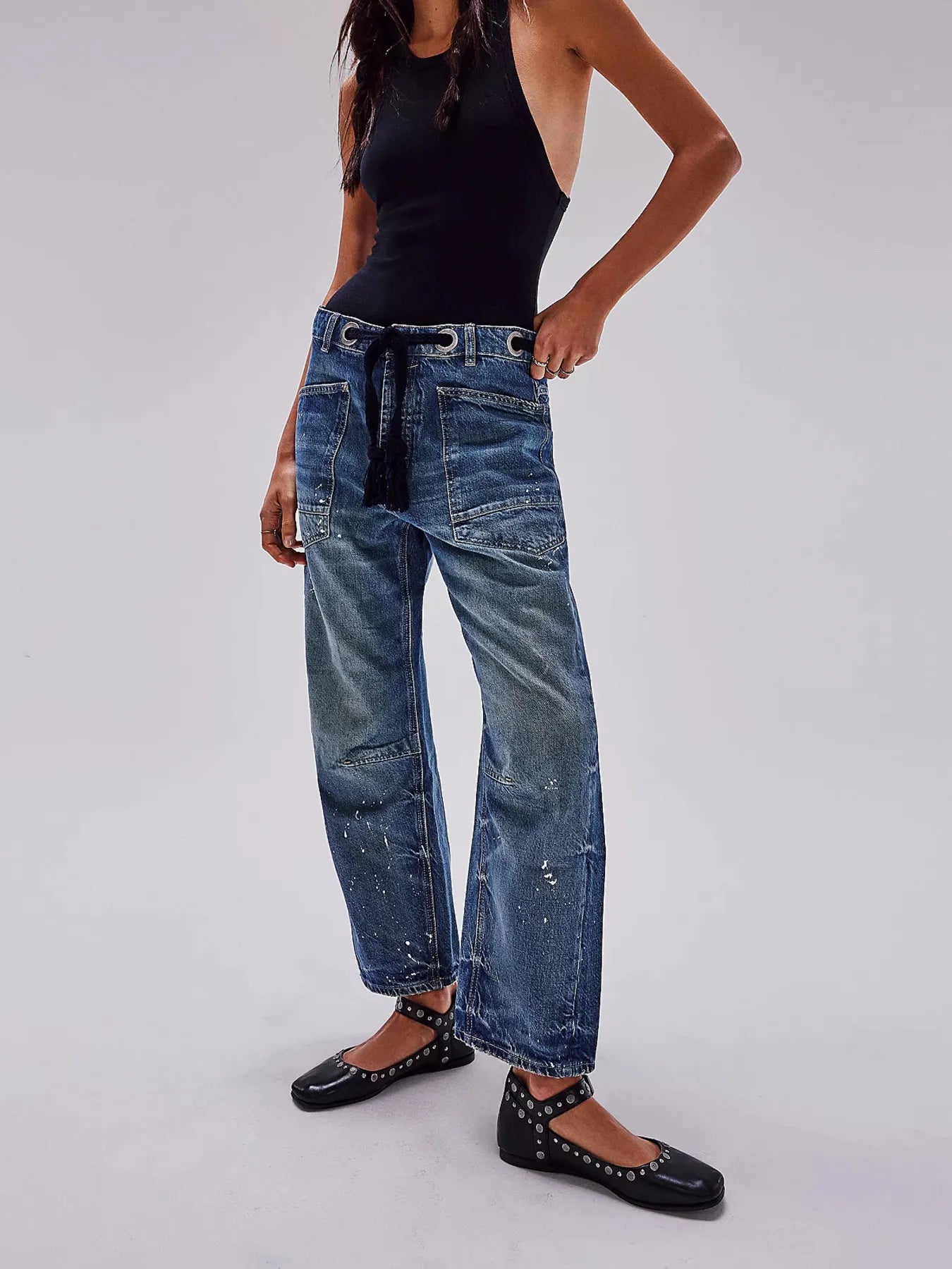 Person wearing blue jeans and black shoes on a plain background