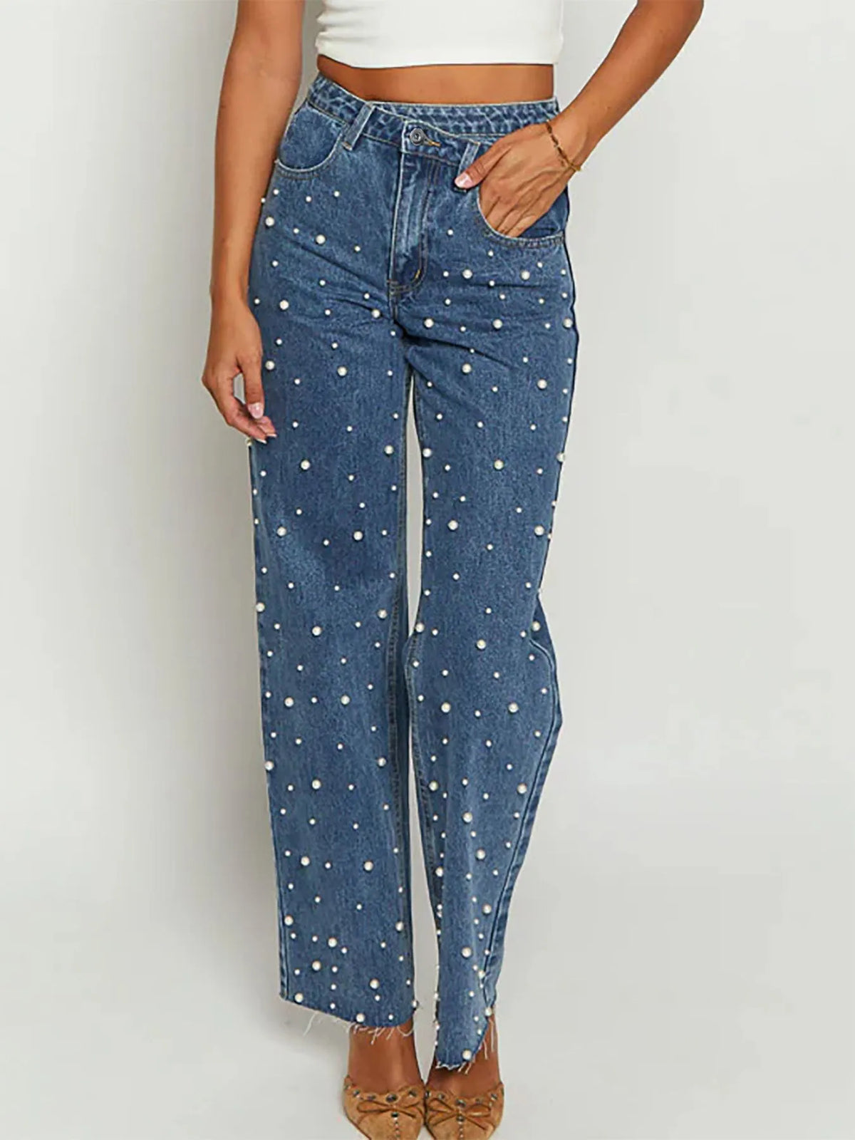 Blue jeans with white polka dots worn by a person on a plain background