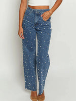 Blue jeans with white polka dots worn by a person on a plain background