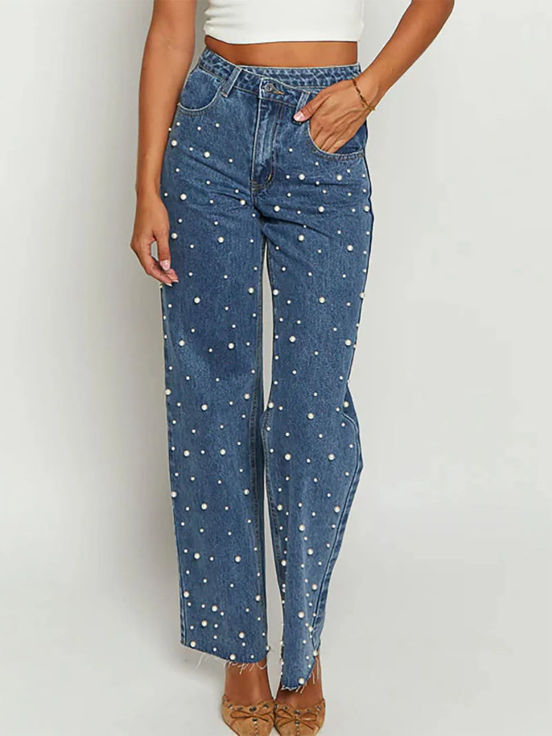 Blue jeans with white polka dots worn by a person on a plain background