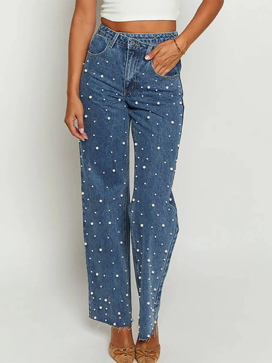 Blue jeans with white polka dots worn by a person on a plain background