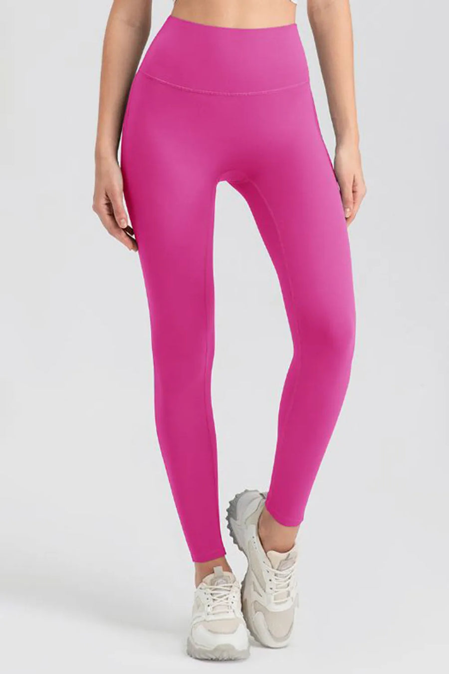 Person wearing bright pink leggings on a white background