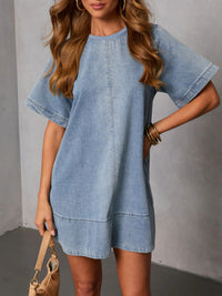 Woman wearing a light blue denim dress against a gray background