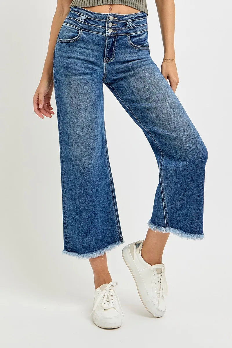 Person wearing blue wide-leg jeans and white sneakers on a white background