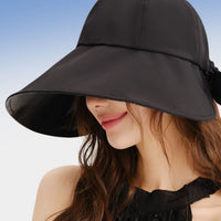 Woman wearing a black sun hat against a clear blue sky