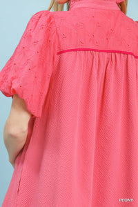 Close-up of a pink dress with intricate detailing on a light blue background