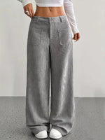 Person wearing gray wide-leg pants with a white top on a plain background