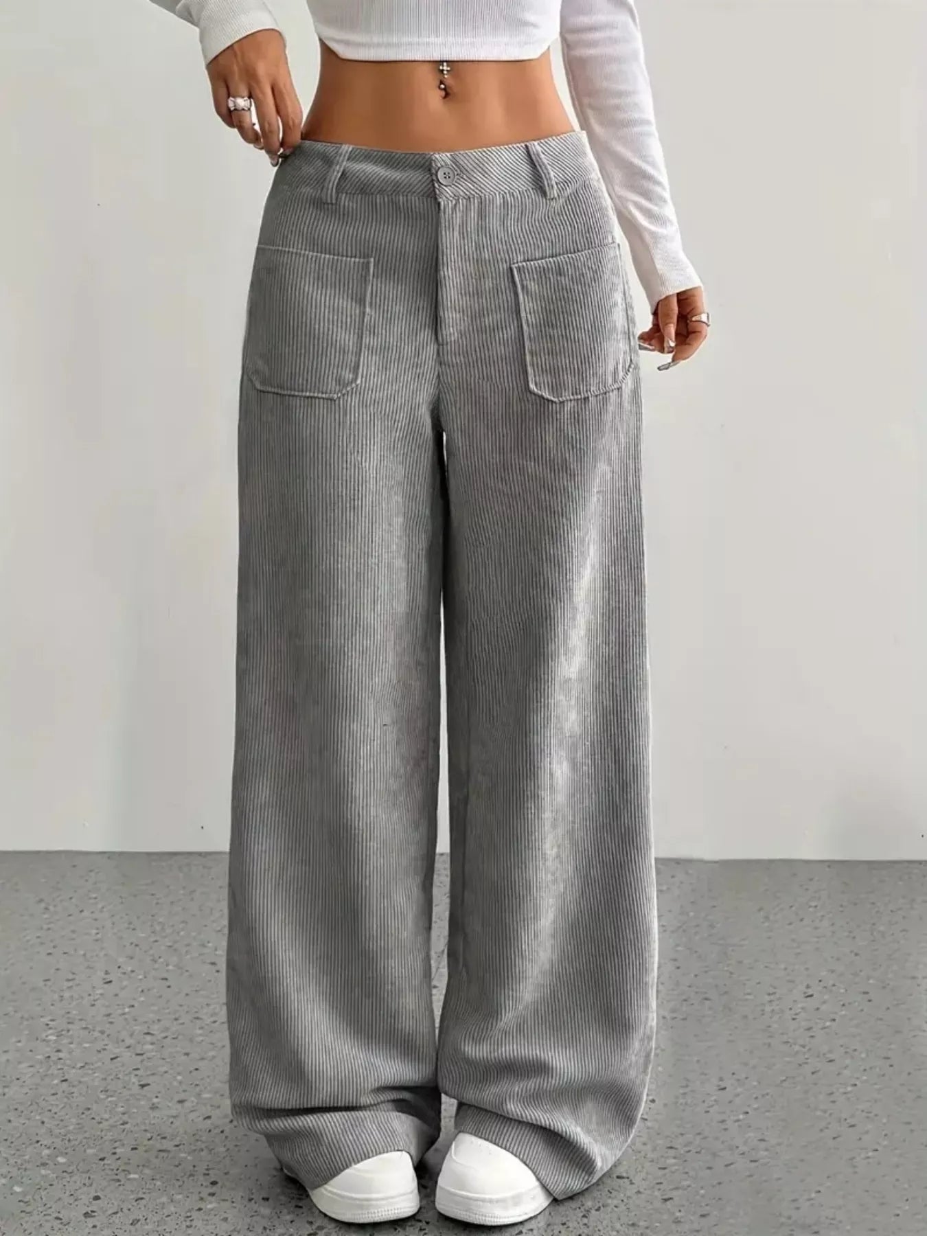 Person wearing gray wide-leg pants with a white top on a plain background