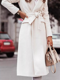 Person wearing a long white coat with a blurred street background