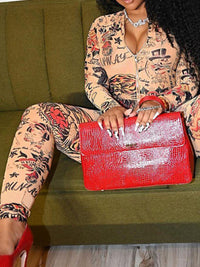 Person wearing a patterned outfit holding a red handbag on a green couch.