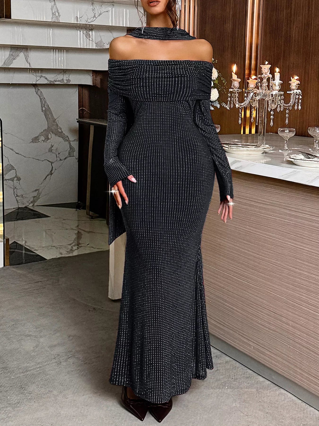 Woman wearing a black off-shoulder dress in an elegant indoor setting.