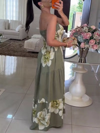 Woman in a floral dress taking a mirror selfie in a living room.