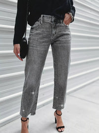 Person wearing gray jeans with sparkling stones on a light background