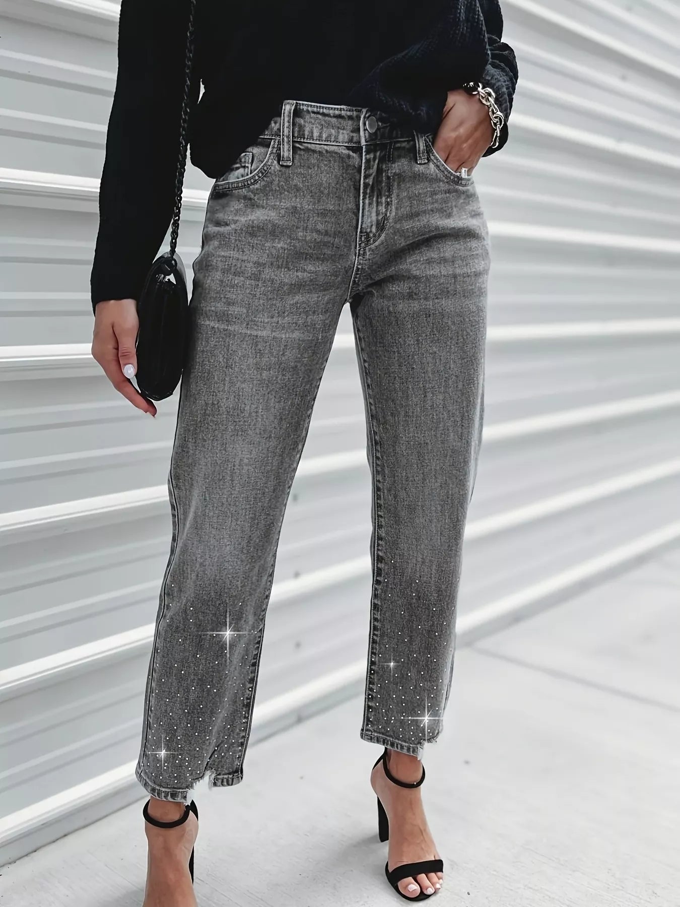 Person wearing gray jeans with sparkling stones on a light background