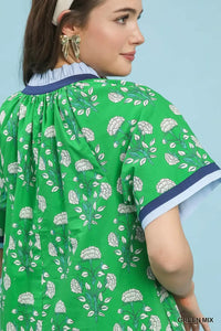 Woman wearing a green dress with floral pattern against a light blue background