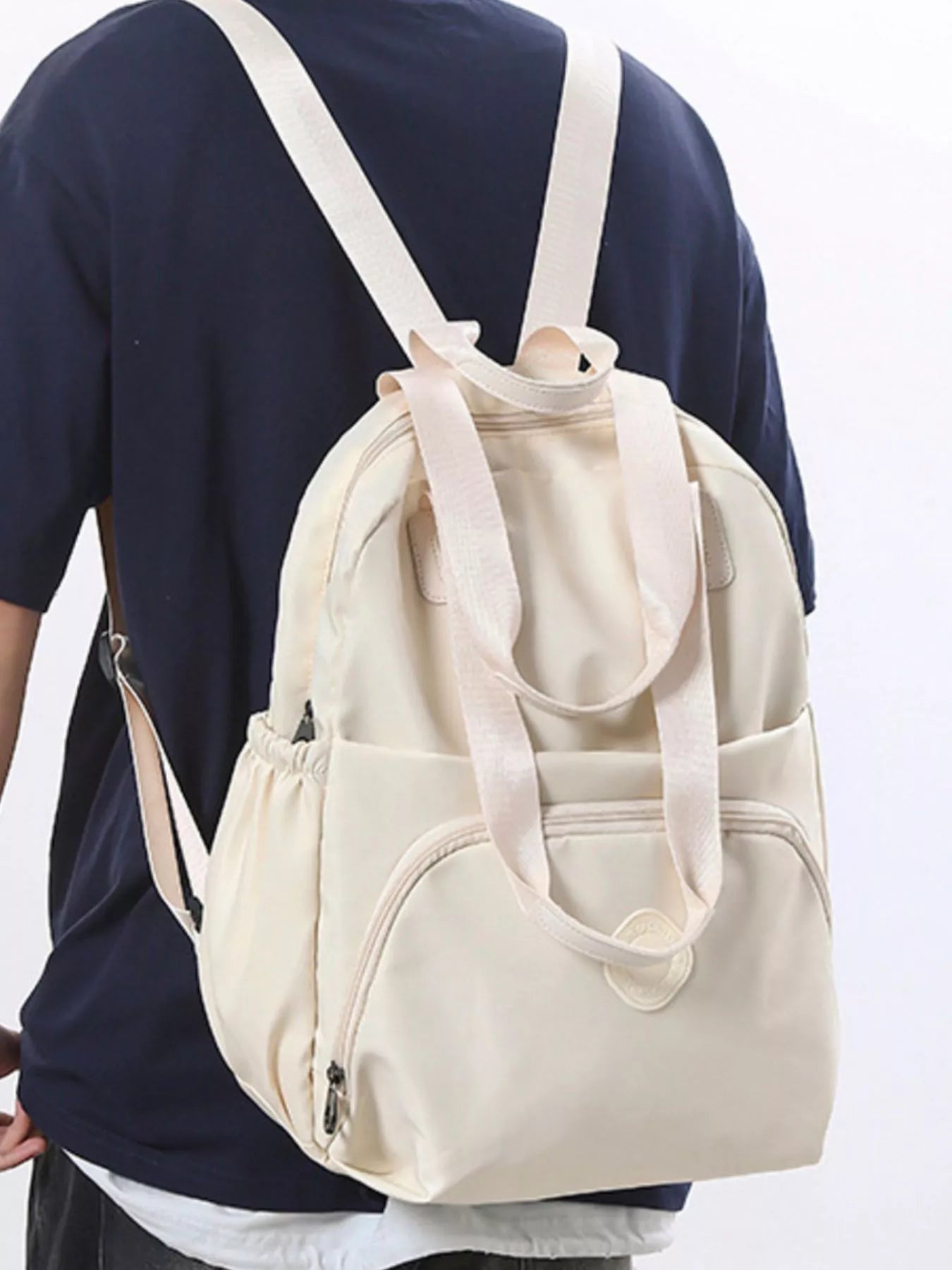 Beige backpack worn by a person on a white background