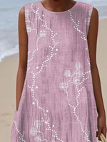 Person wearing a pink dress with white floral patterns on a beach.