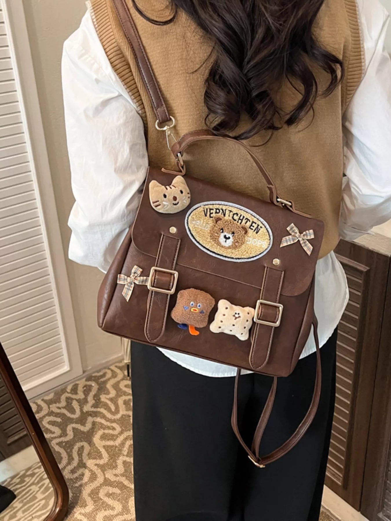 Brown bag with bear-themed decorations worn by a person indoors.