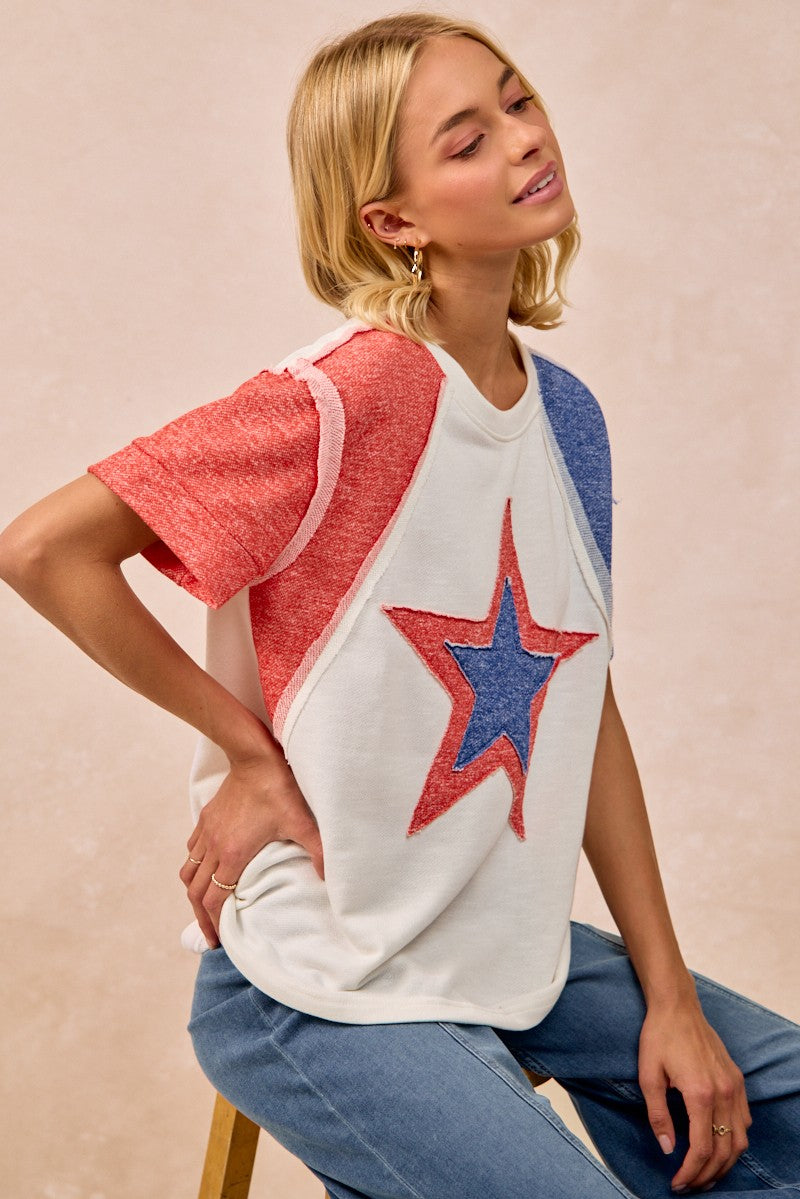 Woman wearing a colorful star-patterned top against a beige background