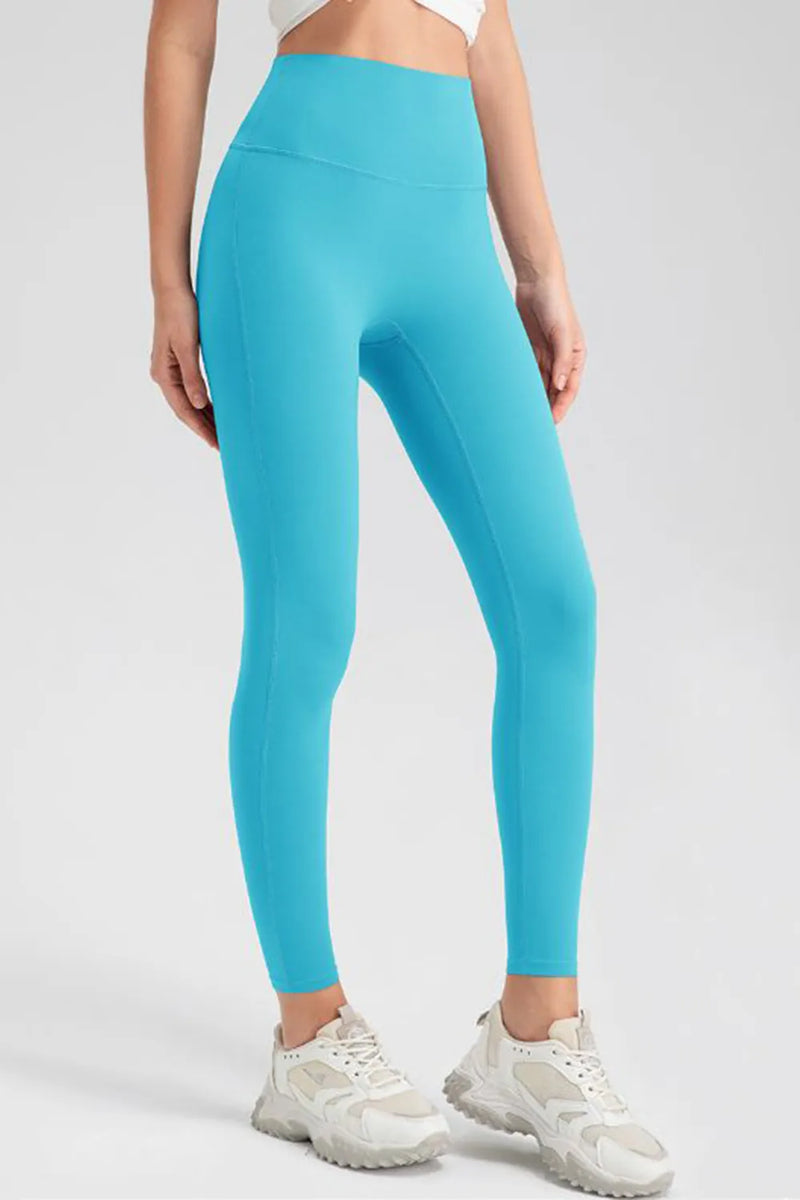 Person wearing turquoise leggings and white sneakers on a light gray background