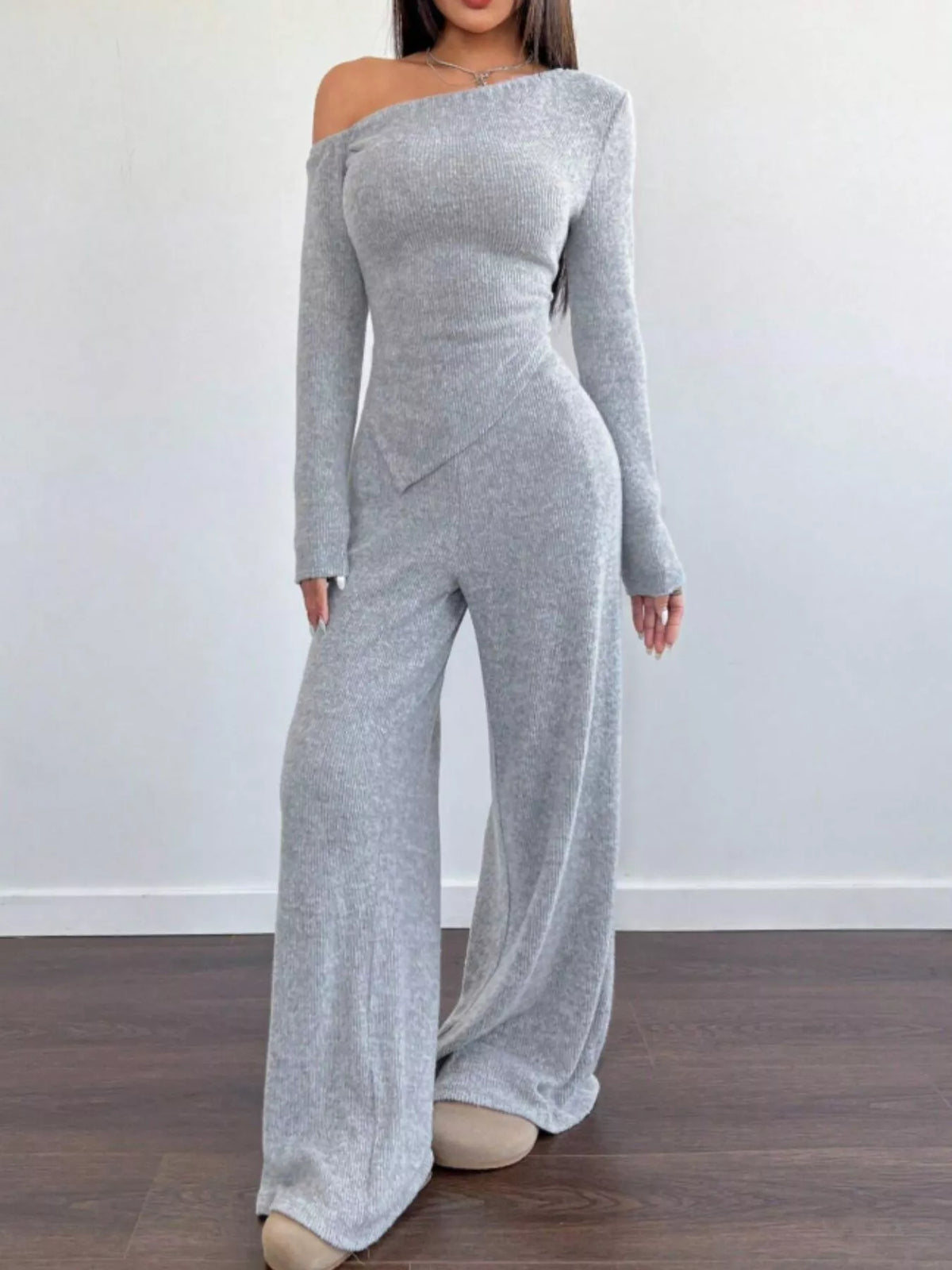 Gray off-shoulder jumpsuit worn by a person on a plain background
