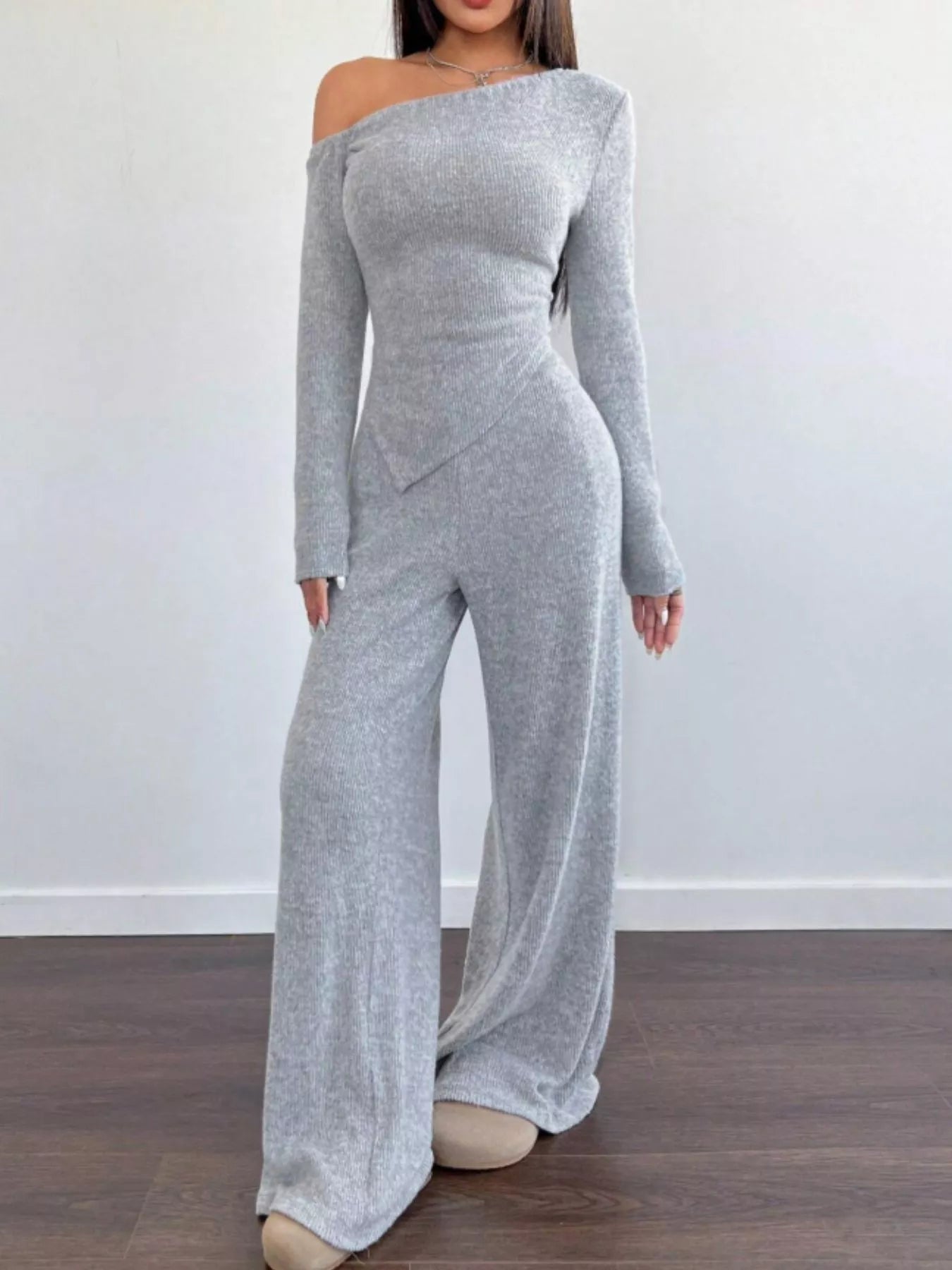 Gray off-shoulder jumpsuit worn by a person on a plain background