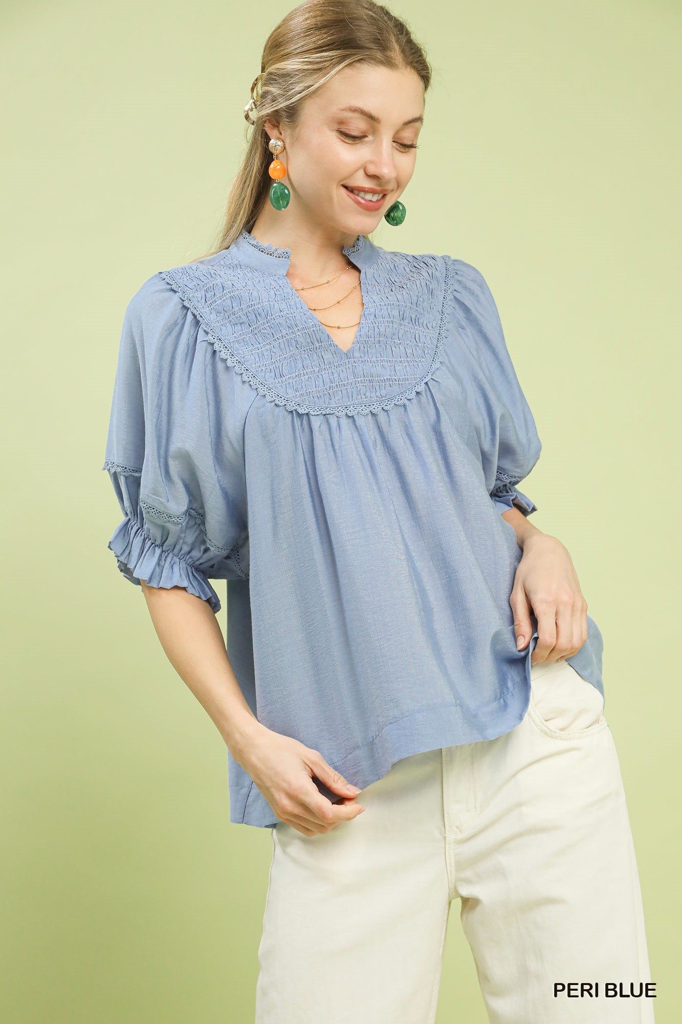 Woman wearing a blue blouse with ruffled details on a light green background