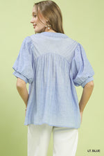 Woman wearing a light blue blouse against a green background