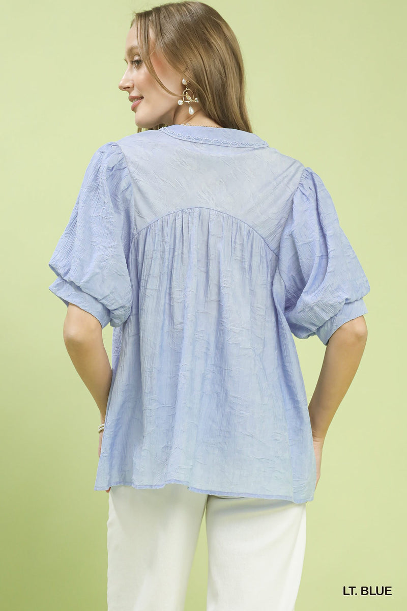 Woman wearing a light blue blouse against a green background