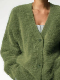 Green cardigan worn by a person on a white background