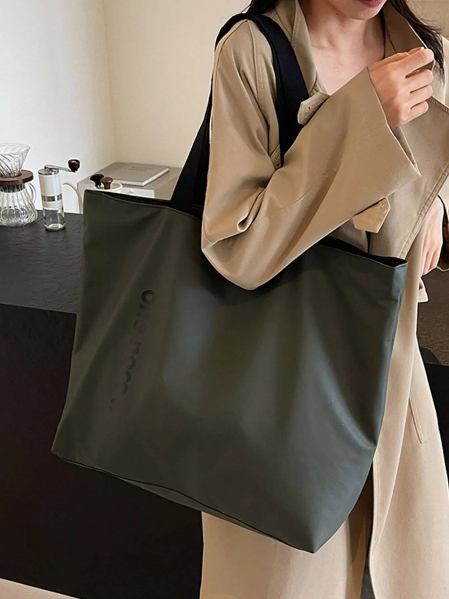 Person holding a green tote bag with a blurred indoor background