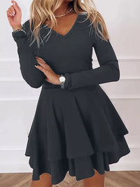 Black long-sleeve dress worn by a person on a white background