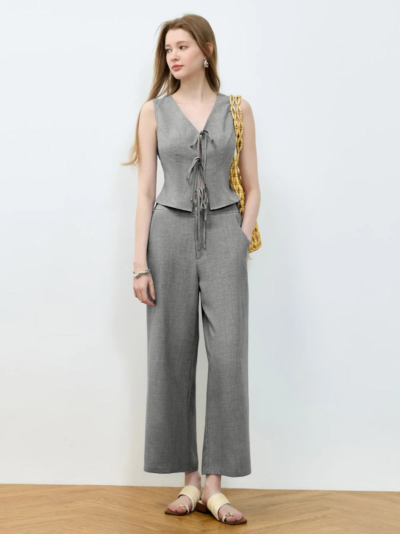 Woman wearing a gray sleeveless top and wide-leg pants against a white background
