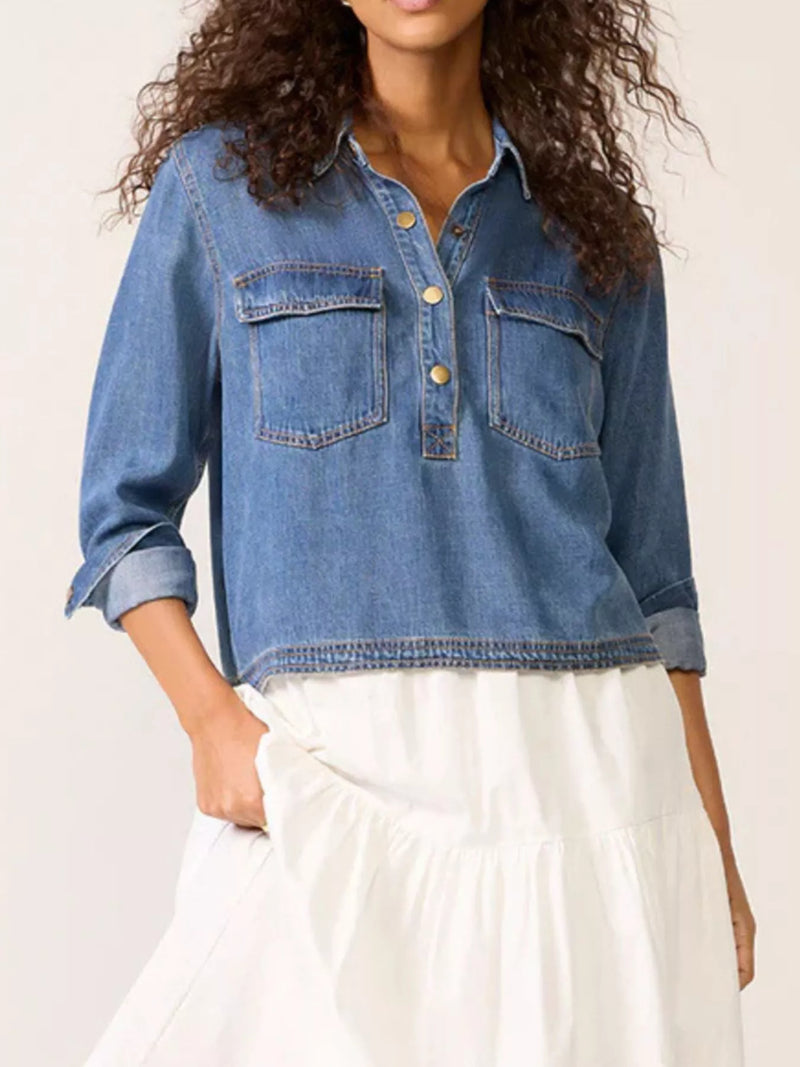 Person wearing a blue denim shirt with a plain background