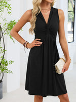 Woman wearing a black dress holding a white clutch in a bright room.