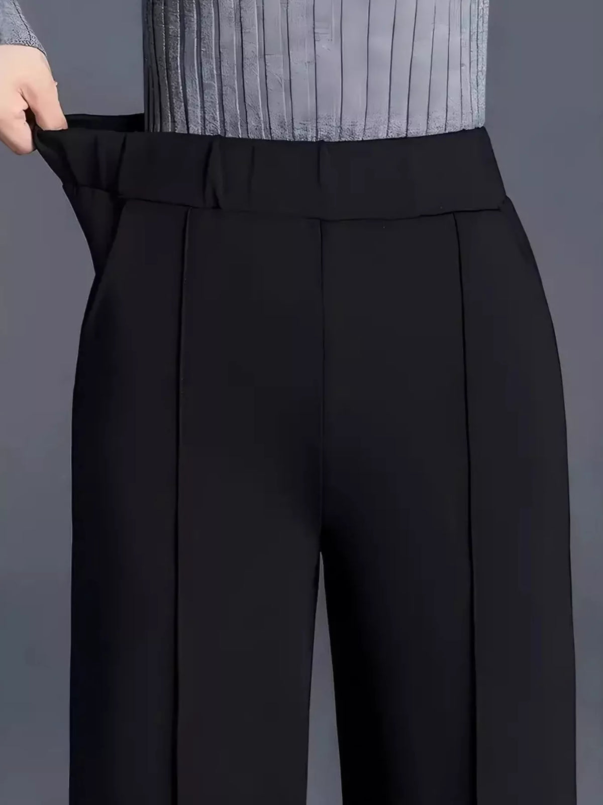 Black pants being adjusted against a gray background