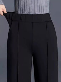 Black pants being adjusted against a gray background