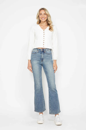 Woman wearing light blue jeans and a white top on a white background